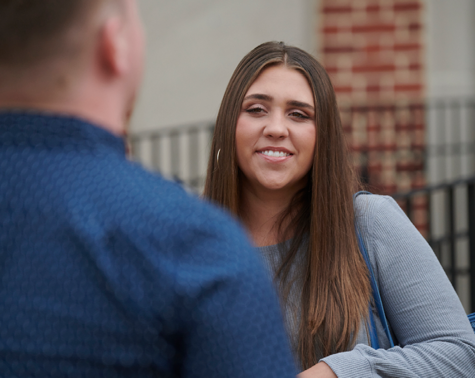 A picture of a student smiling and conversing with someone.